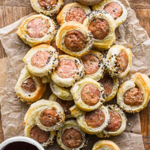 Chicken in a blanket in a pile on a tray.