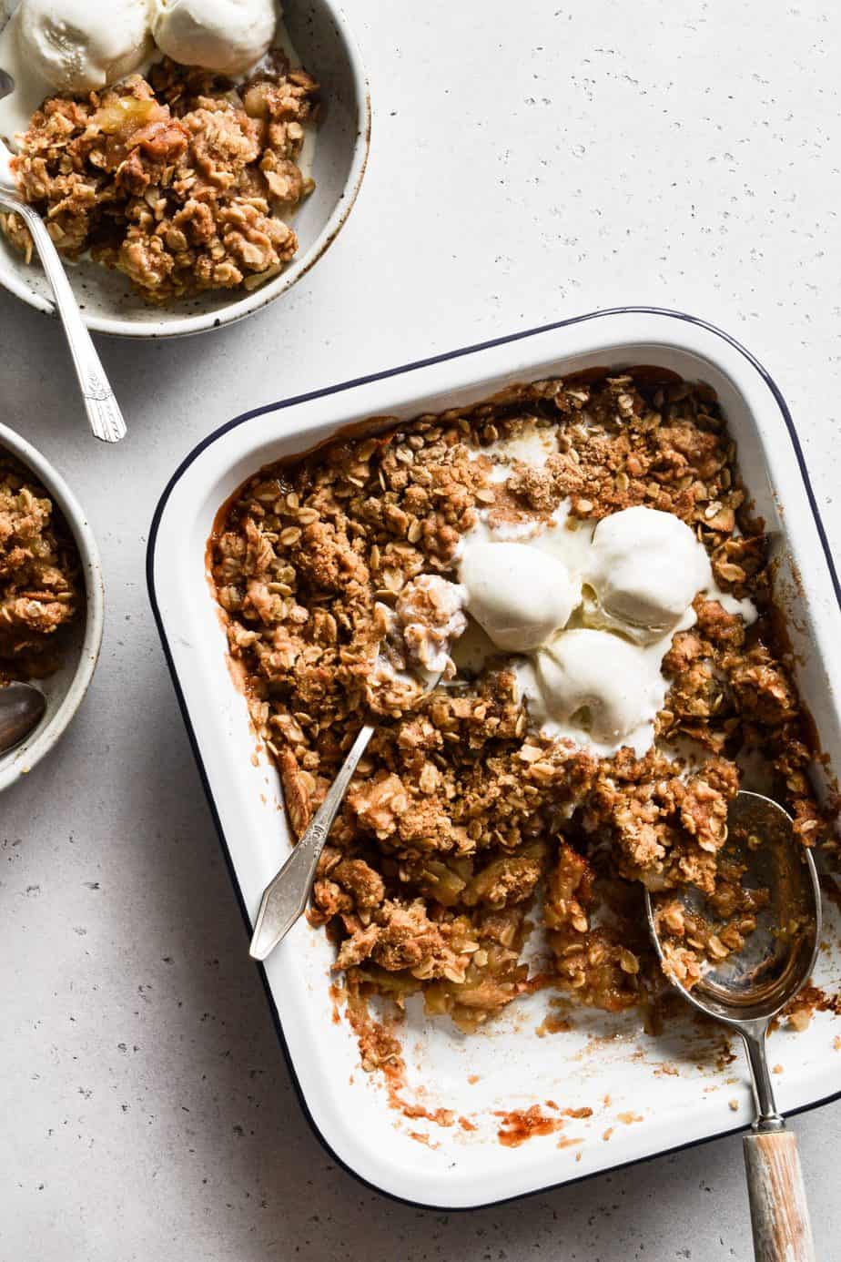 apple crisp in a baking dish with ice cream.
