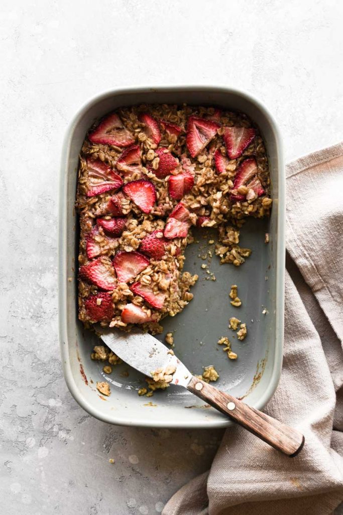 Baking dish of baked oatmeal with a few slices taken.