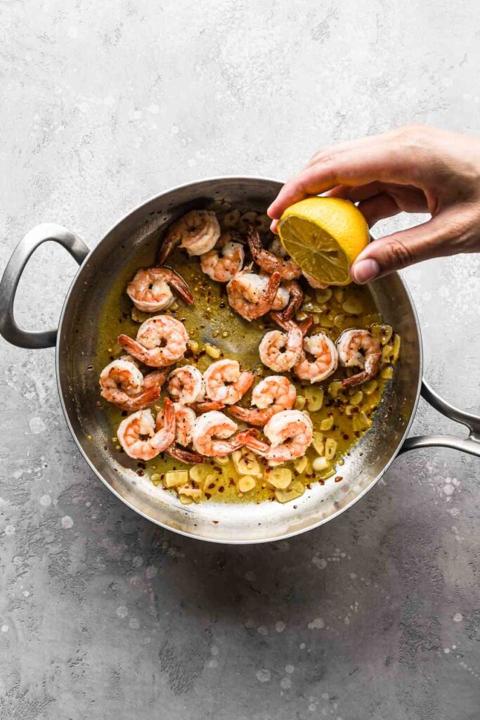 Shrimp added to the sauce with lemon being squeezed in.