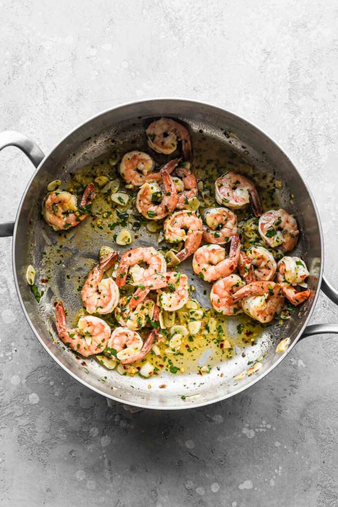 Shrimp tossed together with the sauce in the pan.