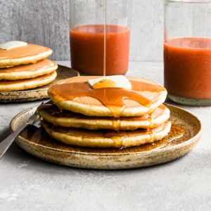 1:1 shot of the pancakes with a pour of maple syrup.