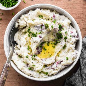 Finished mashed potatoes in a serving bowl with melted butter.