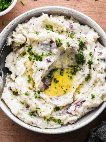 Finished mashed potatoes in a serving bowl with melted butter.