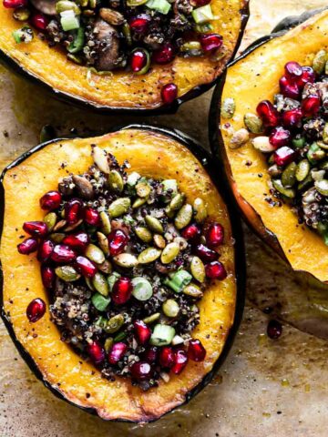 Stuffed acorn squash topped with pomegranate seeds and pepitas.