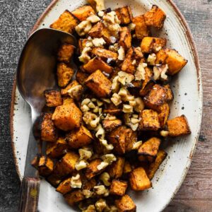 Air fryer butternut squash on a platter topped with chopped walnuts.