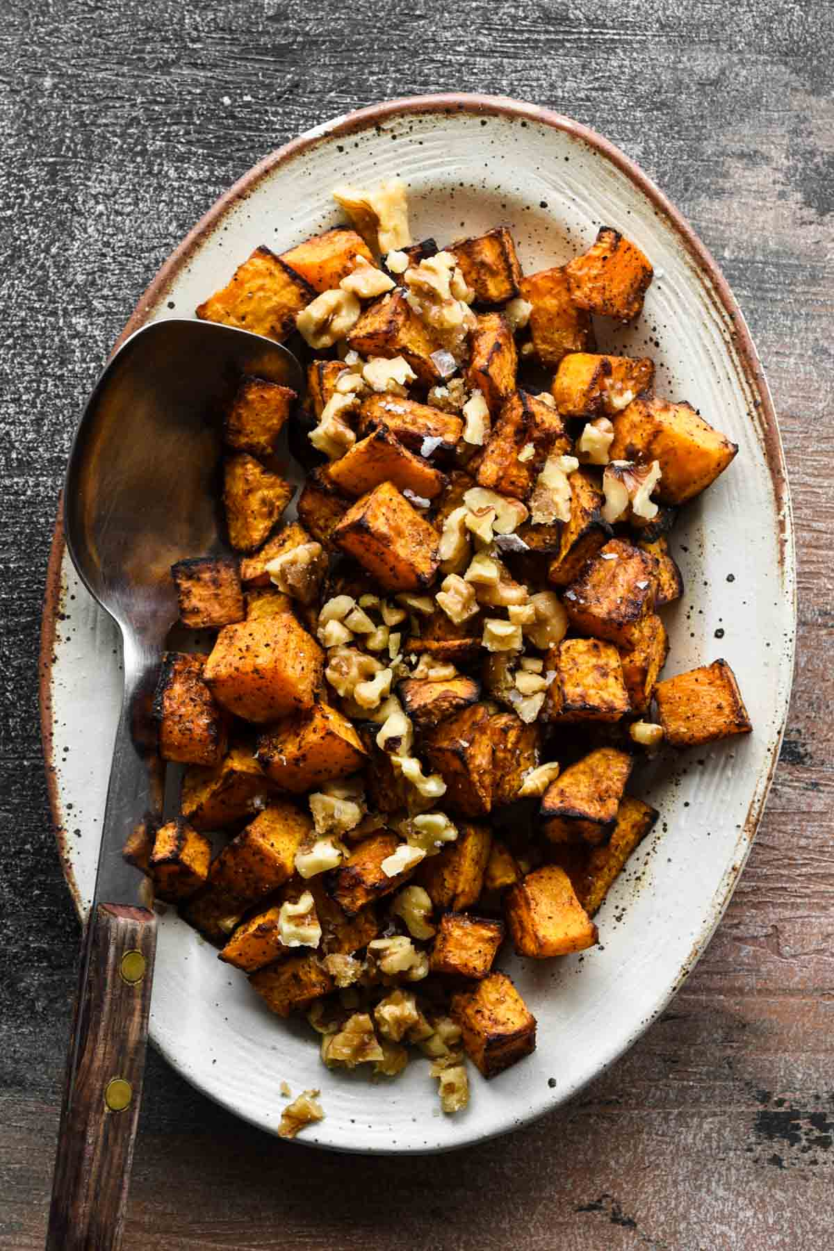 Air fryer butternut squash on a platter topped with chopped walnuts.