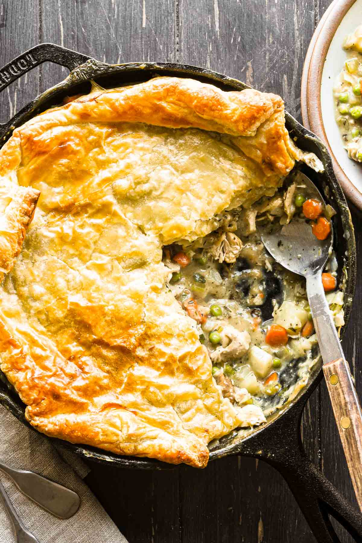 Close up shot of completed puff pastry chicken pot pie dish with a slice removed.
