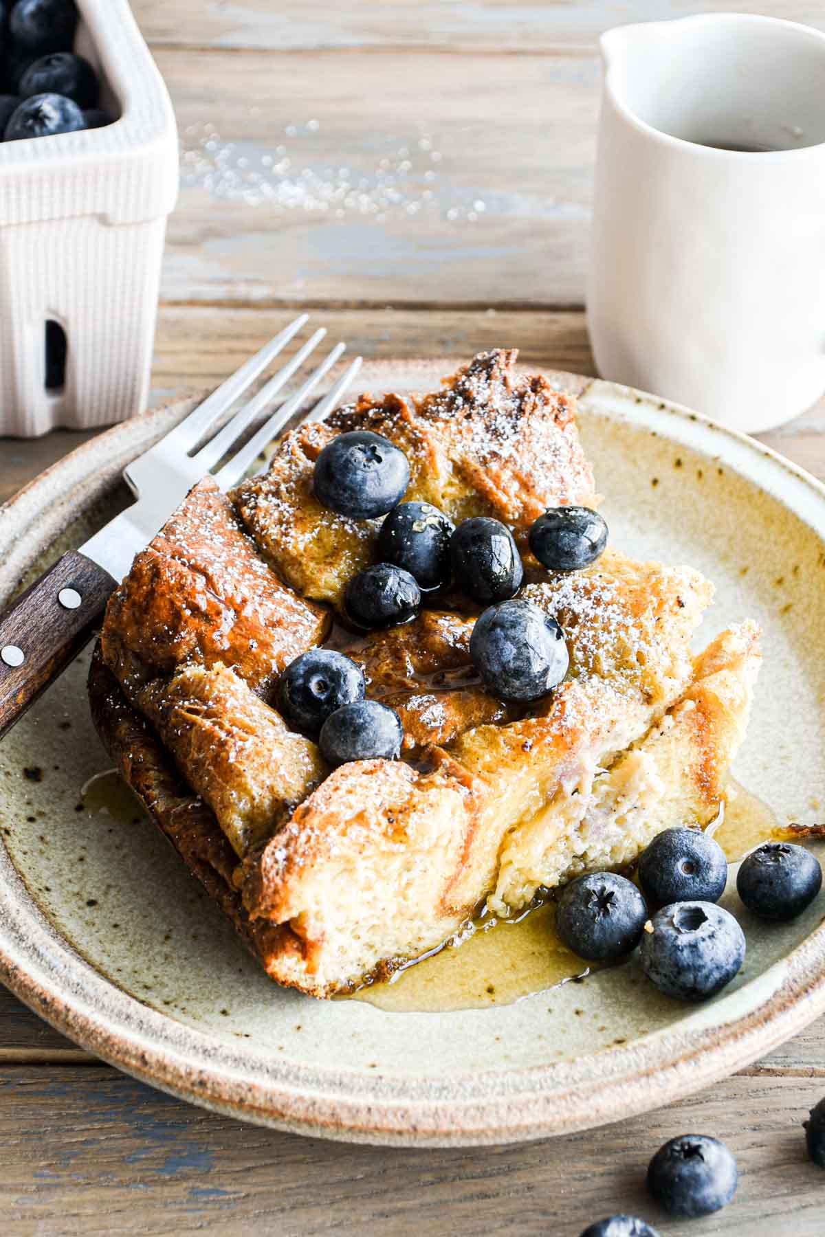 straight-on image of a slice of brioche french toast casserole with blueberries.