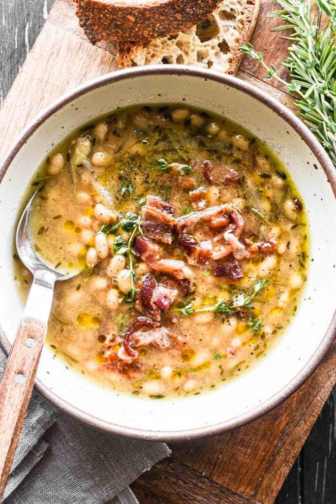 Overhead of beans in a bowl with crusty bread on the side.