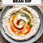 cannellini bean dip in a bowl surrounded by bread.