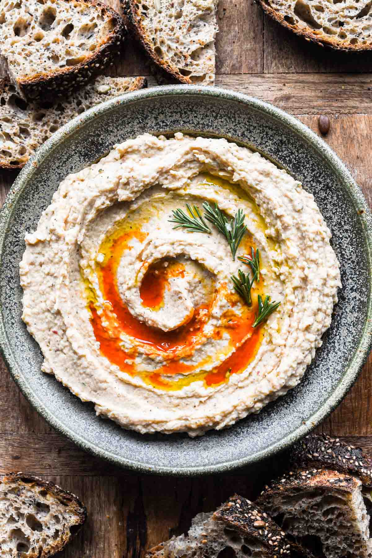 cannellini bean dip in a bowl surrounded by bread.