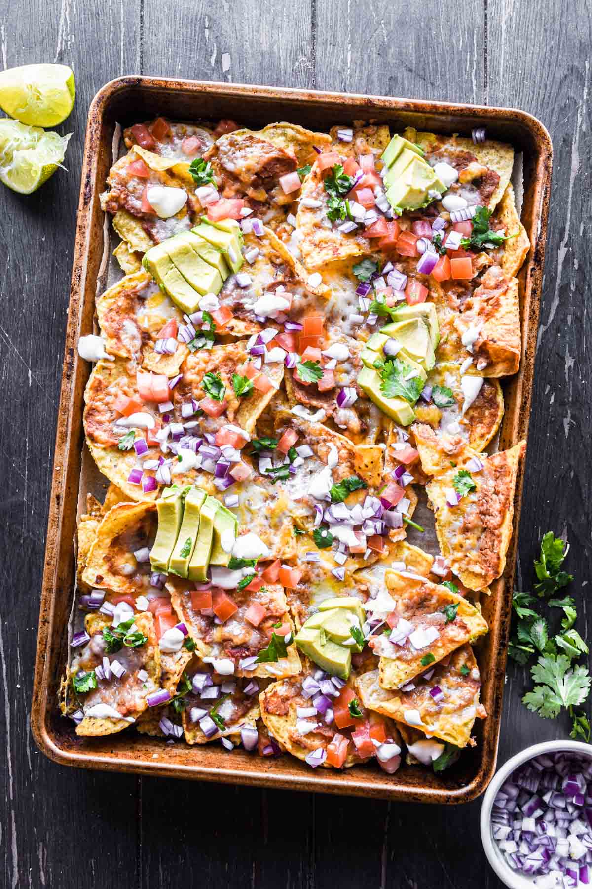 Baked nachos with toppings on a sheet pan.