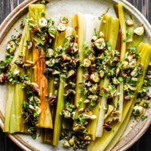 Finished braised and caramelized leeks on a serving plate with gremolata.