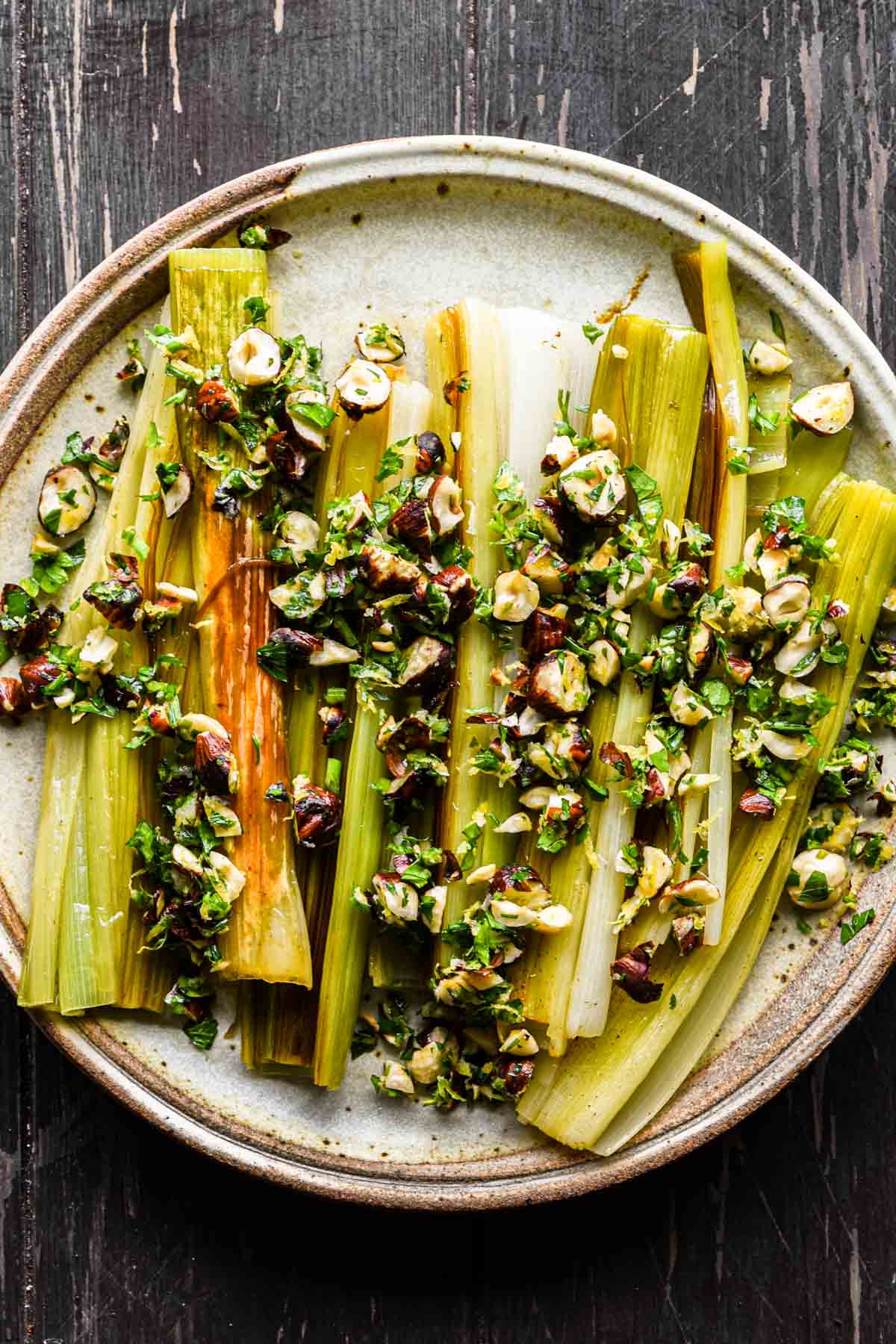 Finished braised and caramelized leeks on a serving plate with gremolata.