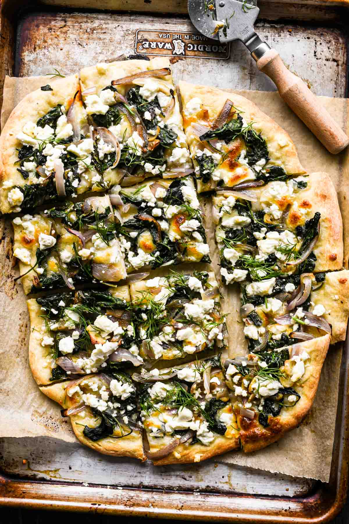 Close up of sliced spinach and feta pizza.