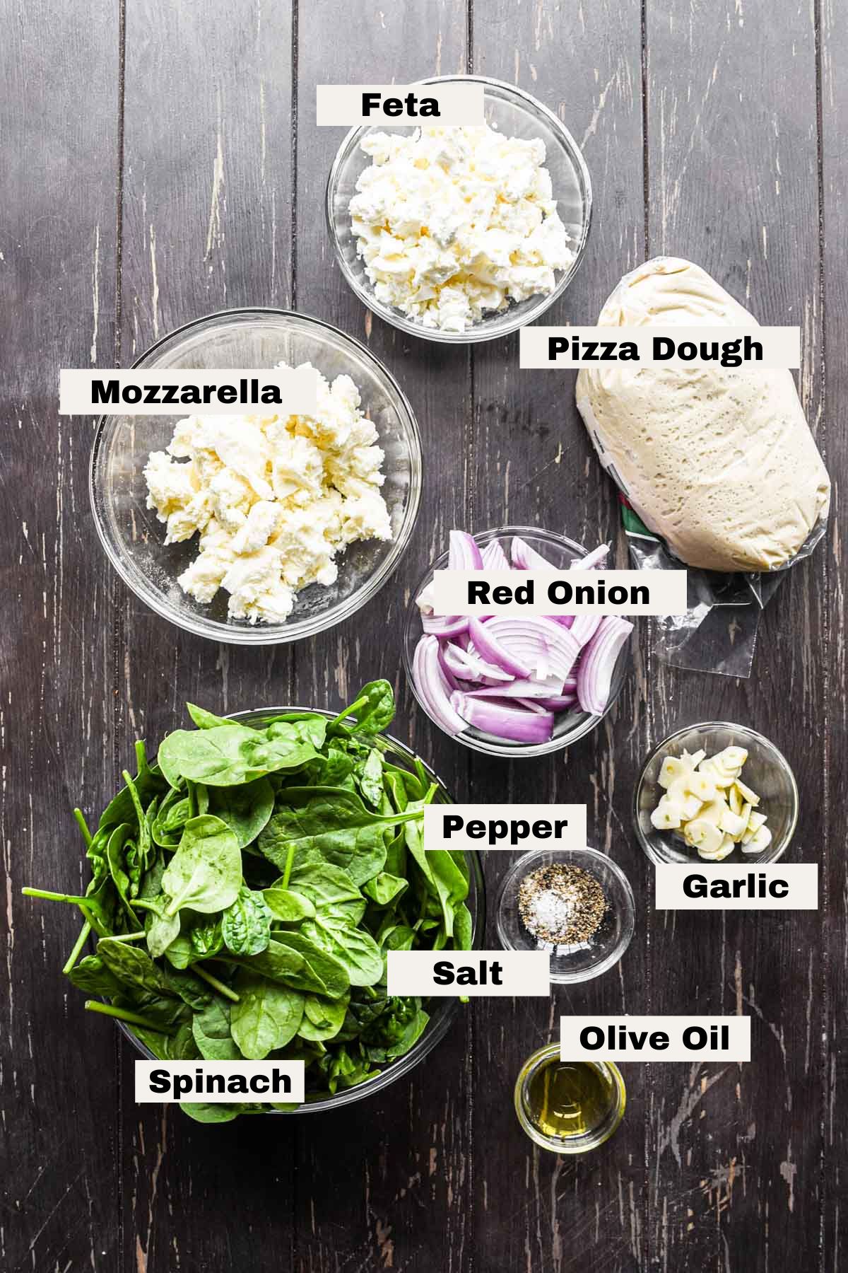 Ingredients for spinach and feta pizza on a table.