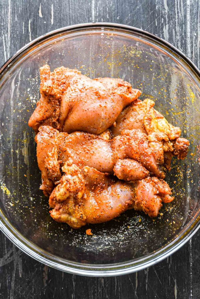 Seasoning the chicken with spices.