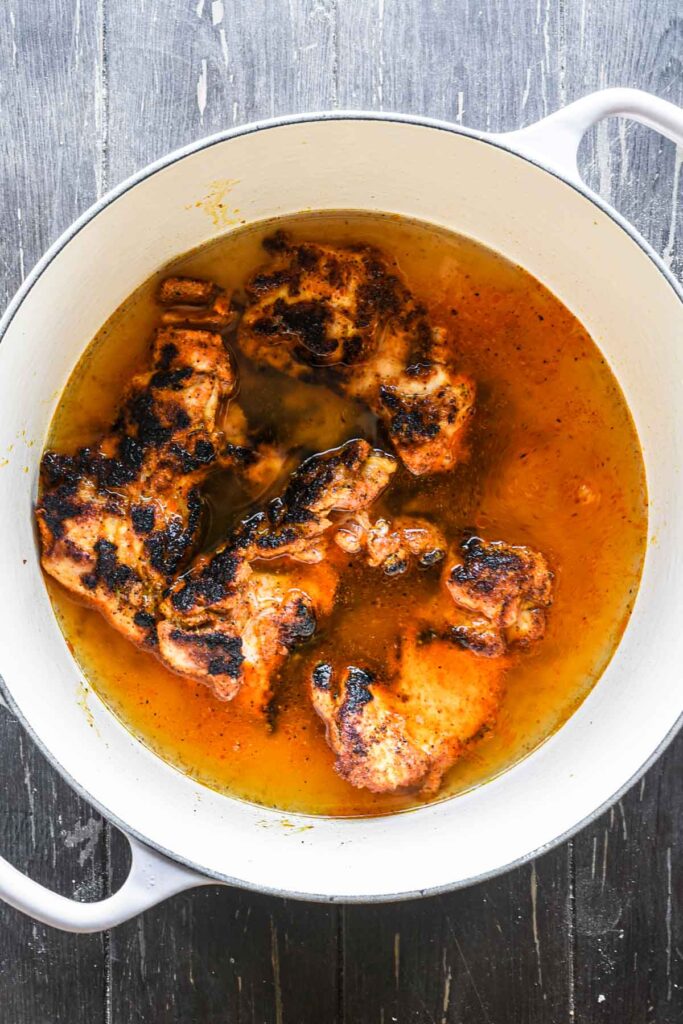 Simmering chicken in the chicken stock.