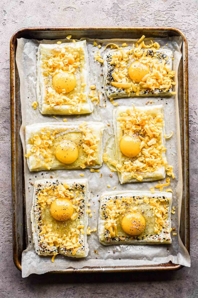 Par-baked puff pastry breakfast egg tarts topped with eggs and cheese.