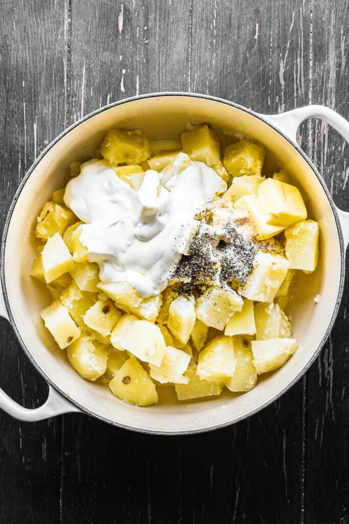 Mixing the cooked potatoes with other mashed potato ingredients.