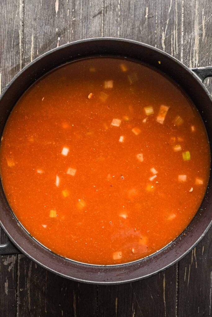 Adding stock and crushed tomatoes to the pot.