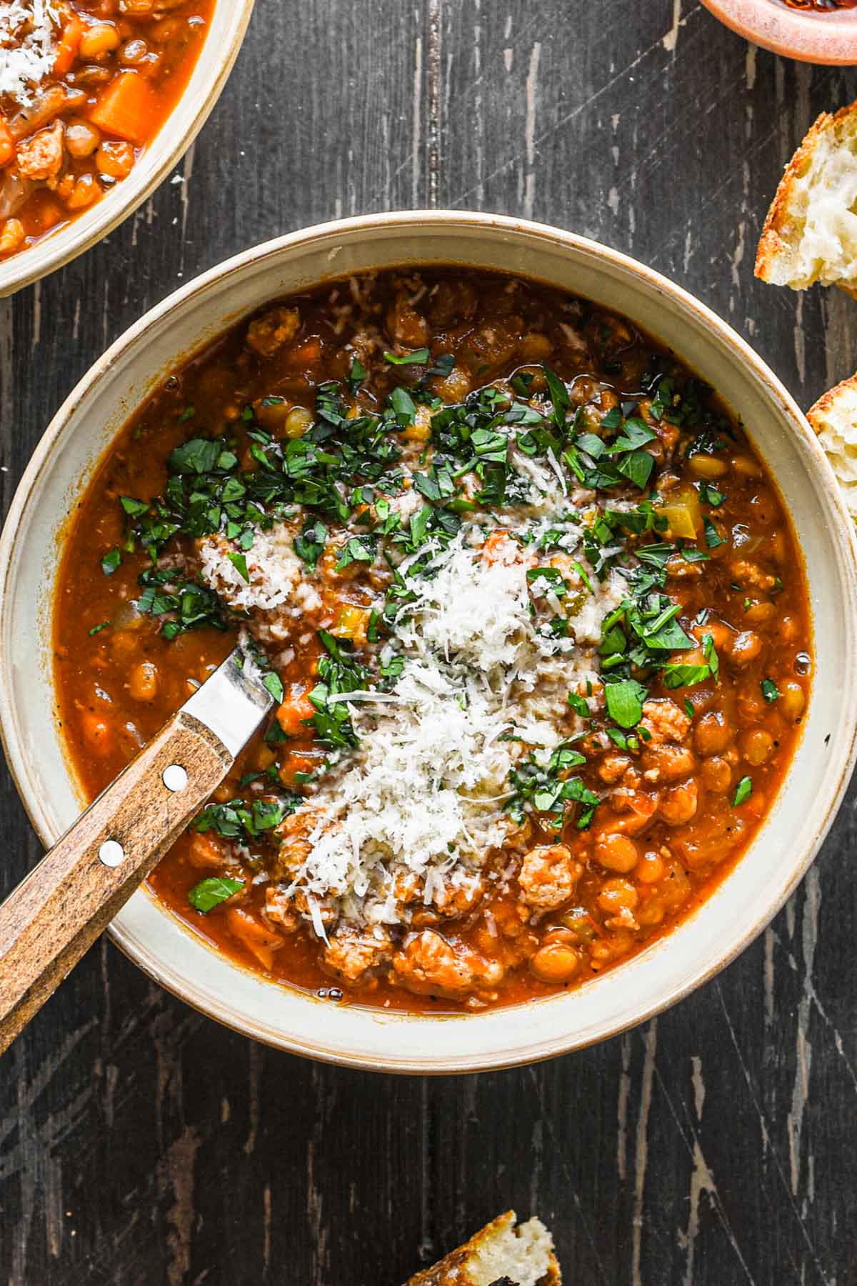 Close up image of turkey lentil soup in a bowl with parsley and parmesan.