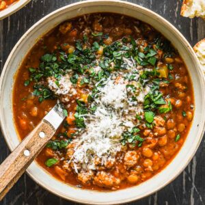 Close up image of turkey lentil soup in a bowl with parsley and parmesan.