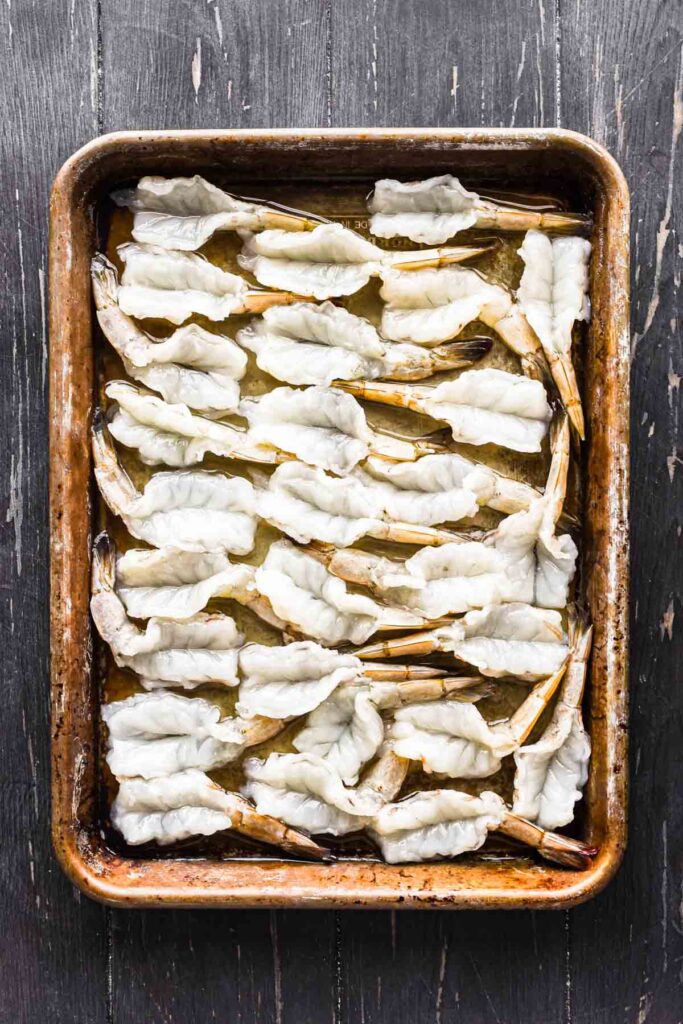Butterflied shrimp on a baking sheet.