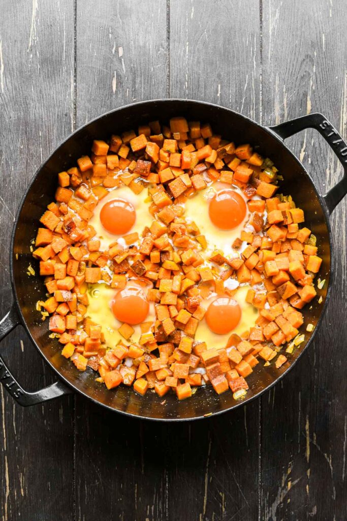 Adding eggs to the cooked potatoes.