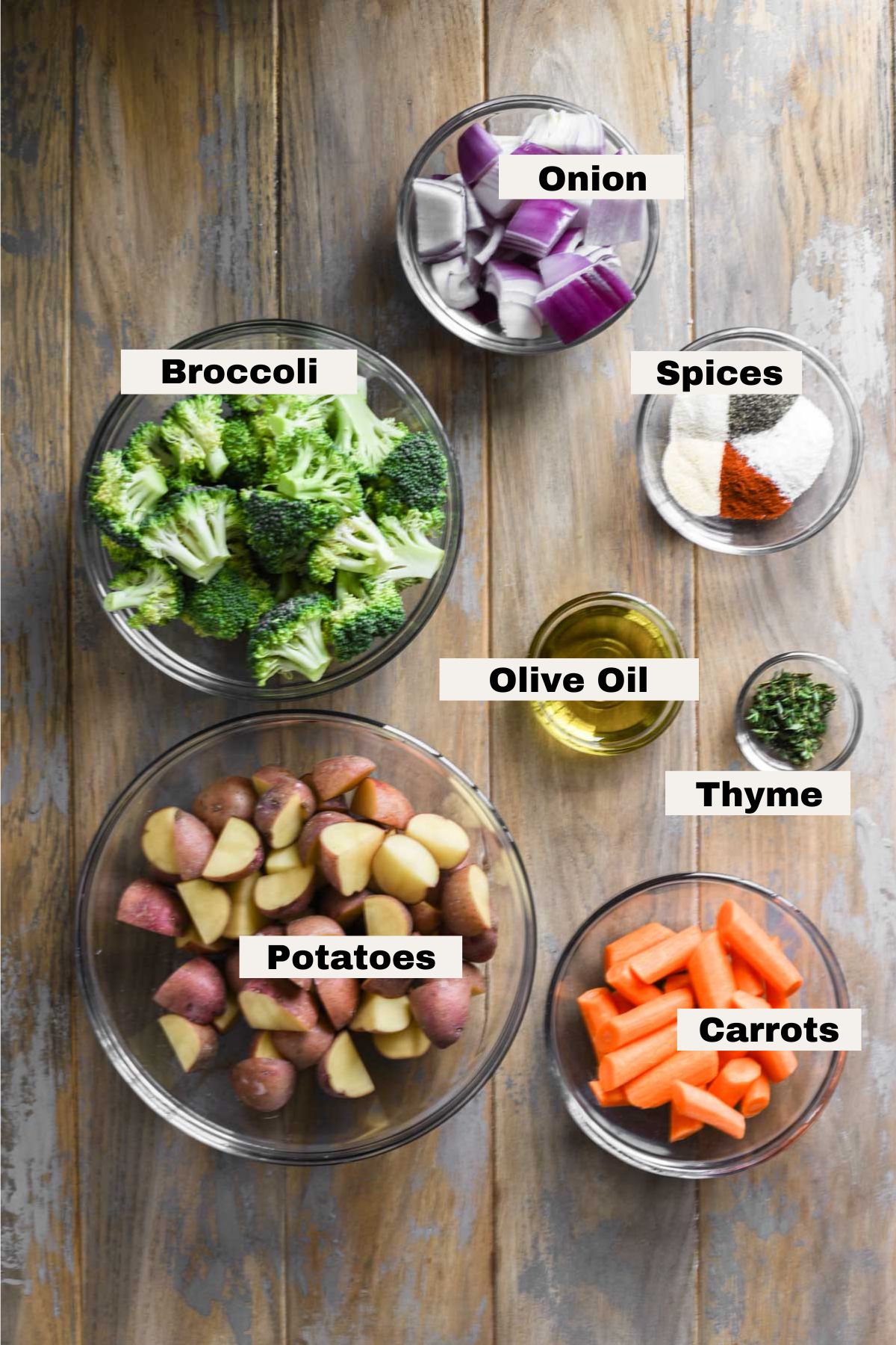 Ingredients for oven roasted vegetables and potatoes on a table.