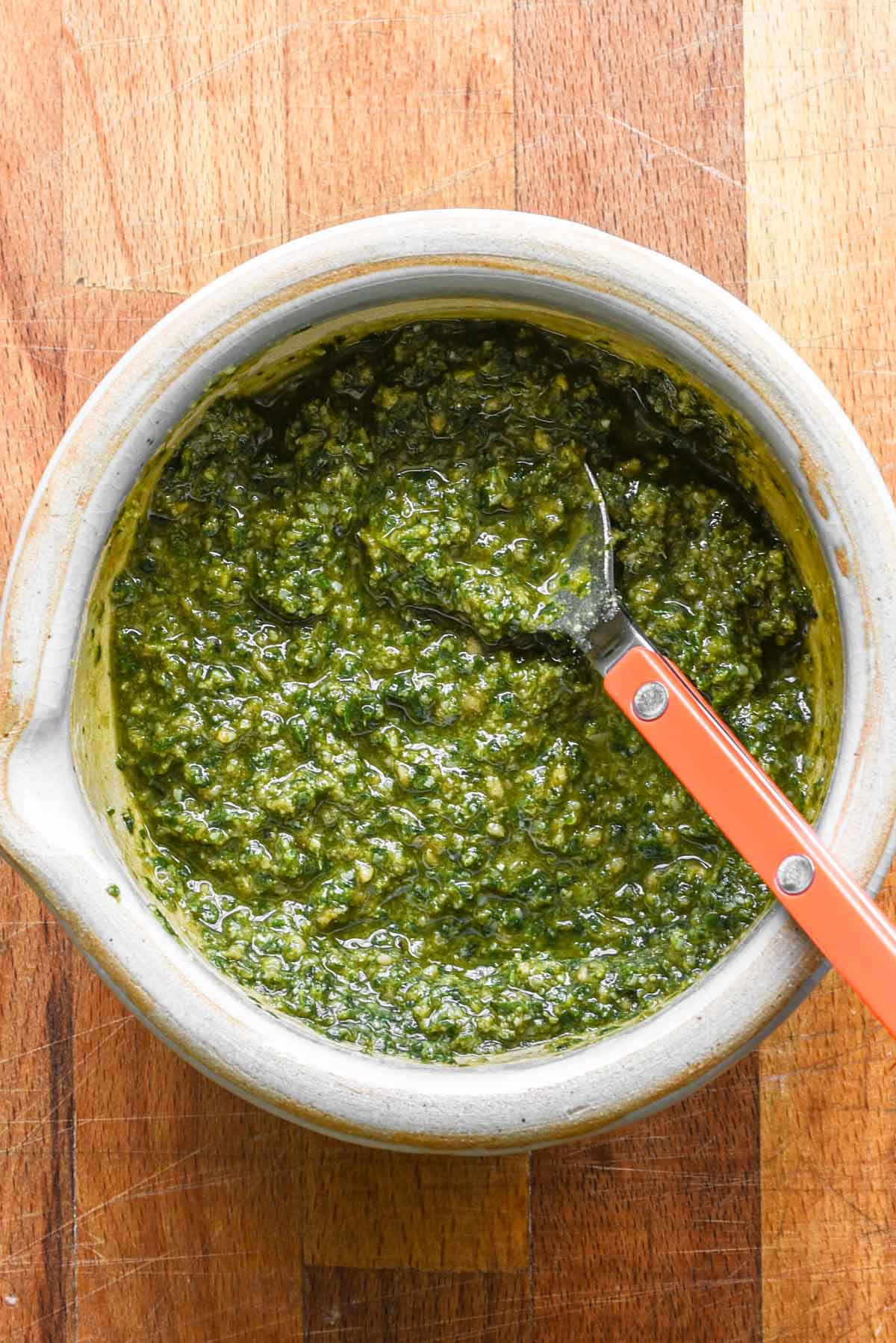 Finished nut free basil pesto in a bowl on a wood table.