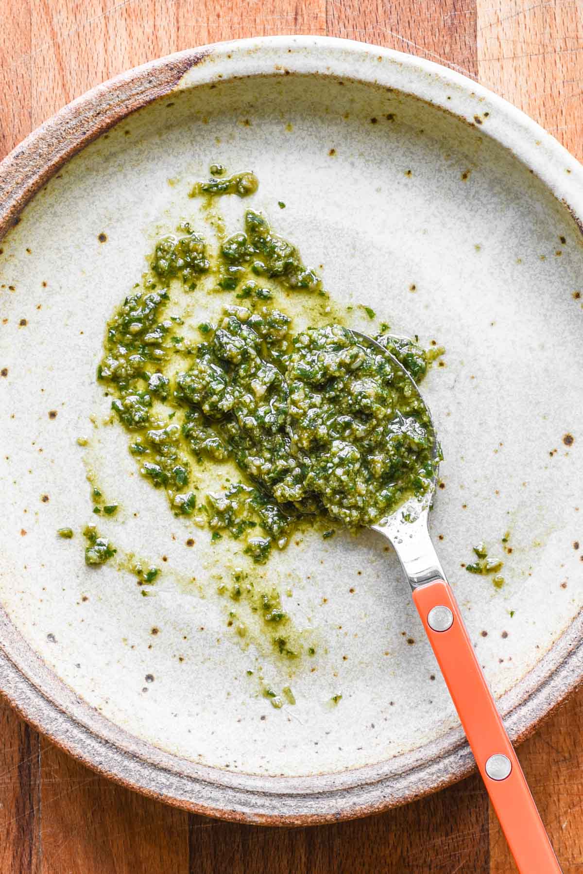 Pesto spread out on a plate with a spoon.