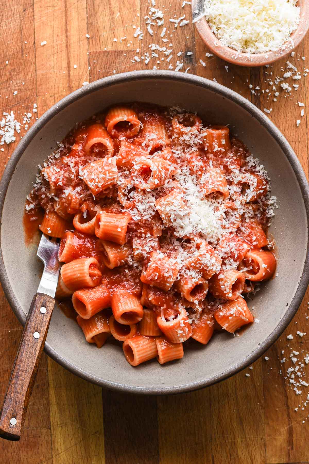 Homemade spicy tomato sauce over pasta in a bowl with parmesan cheese on top.