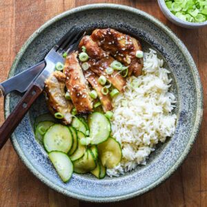 Plated miso chicken thighs with rice and spicy cucumbers.