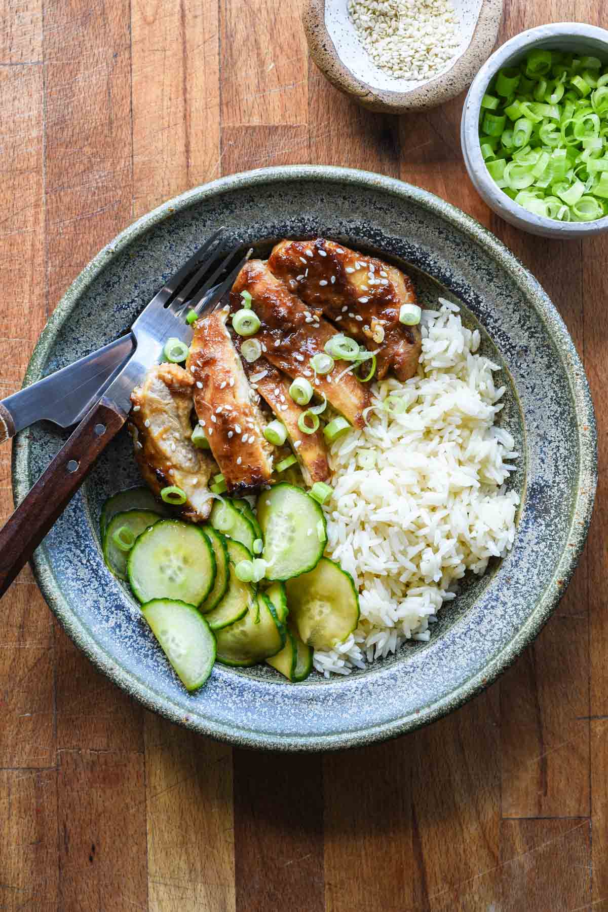 Plated roasted miso chicken thighs with rice and spicy cucumbers.