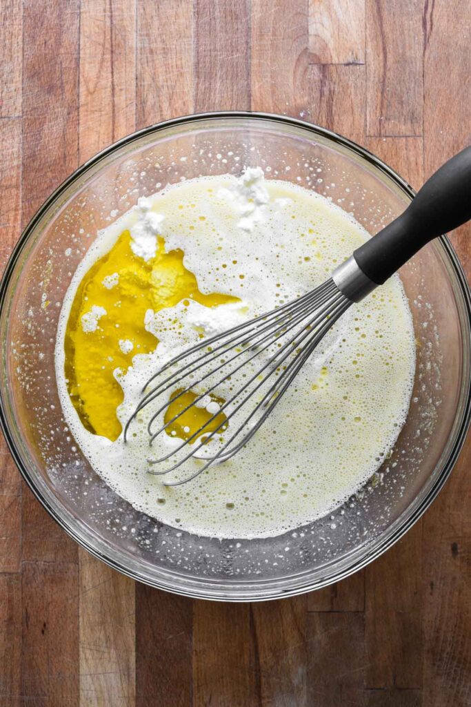 Adding milk, oil, and ricotta to eggs and sugar.