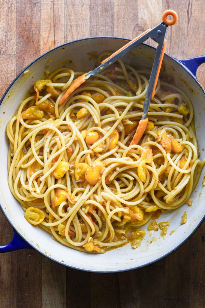 Pasta and pasta water added to skillet with sauce to emulsify.