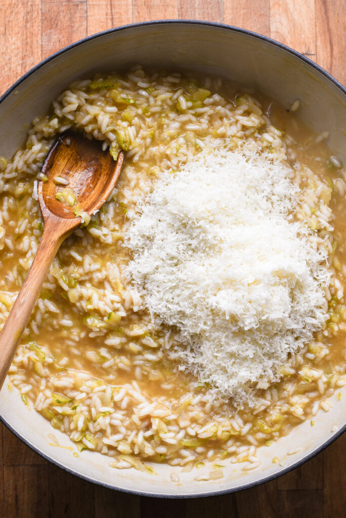 Adding lemon juice, zest and parmesan cheese to risotto.