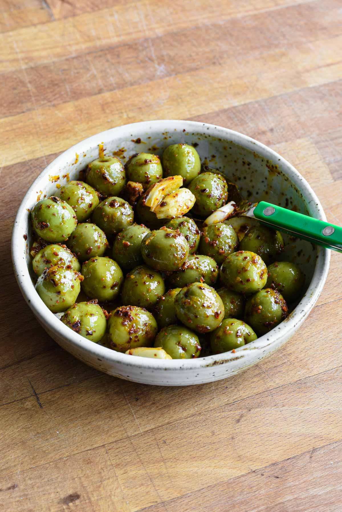 Marinated green olives on a wood table.