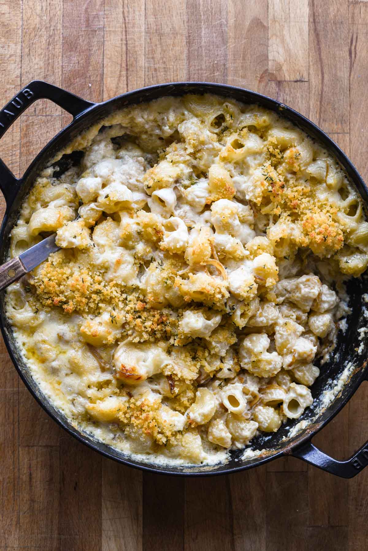 Mac and cheese being scooped out of the skillet.