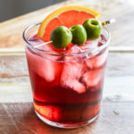 Lambrusco spritz with olives and orange slice.