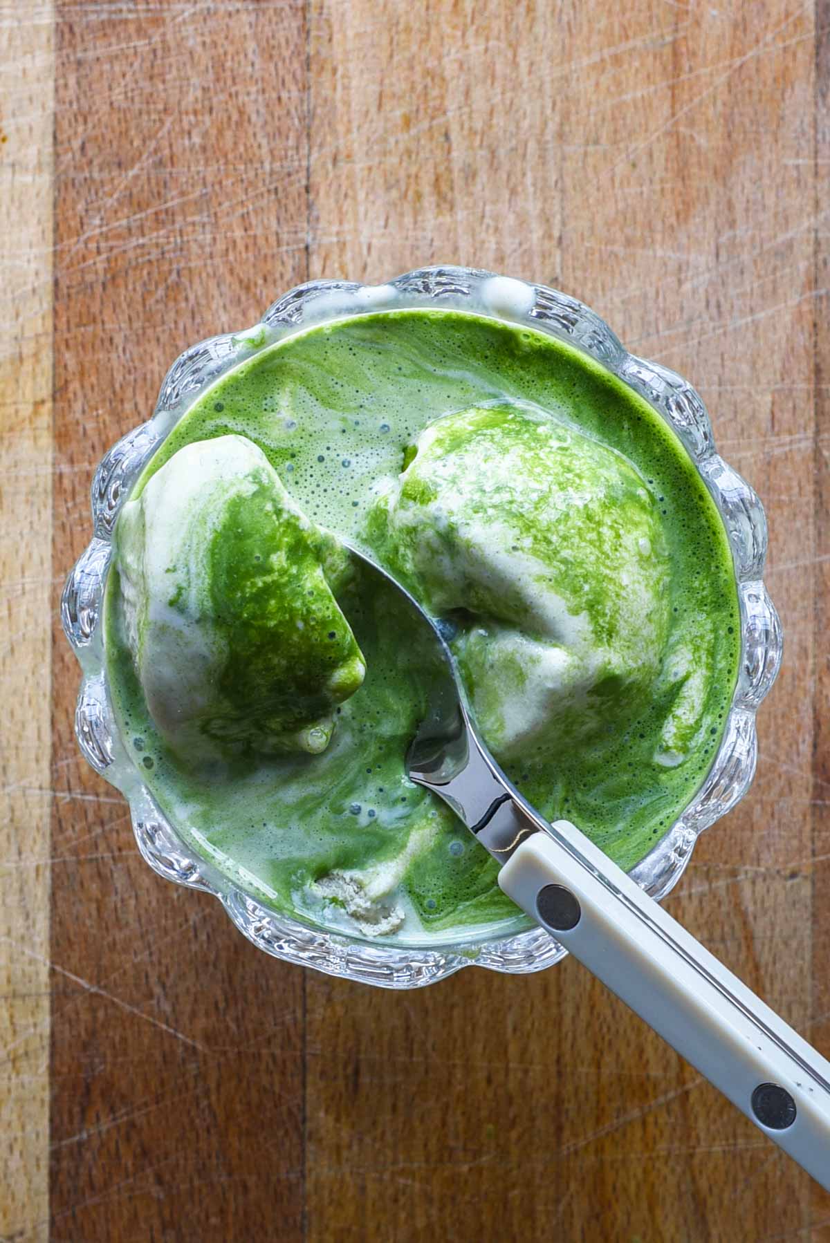 Matcha affogato in a clear ice cream bowl.