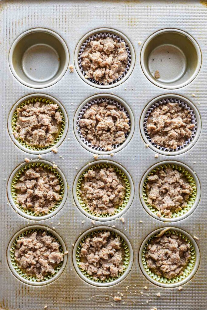 Muffins filled with crumb topping before baking.