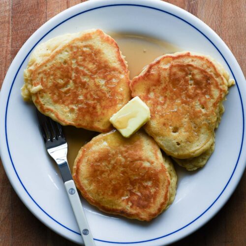 Close up of pancakes with a pat of butter and pure maple syrup.