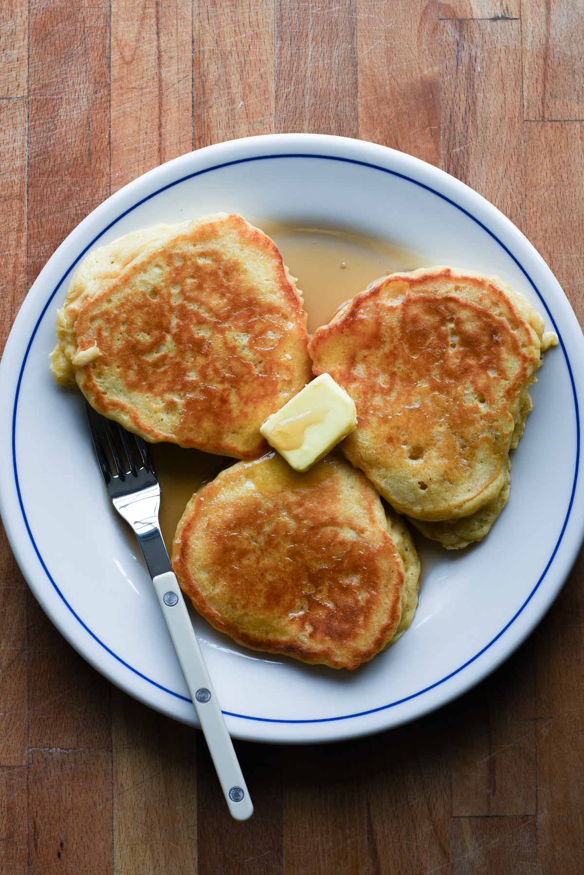 Close up of pancakes with a pat of butter and pure maple syrup.