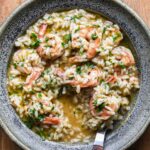 Shrimp scampi risotto in a blue bowl with a wood fork.