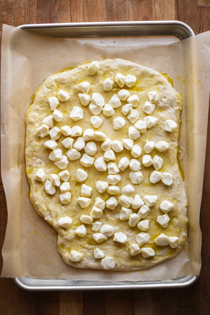 Pizza dough topped with olive oil and cheese.