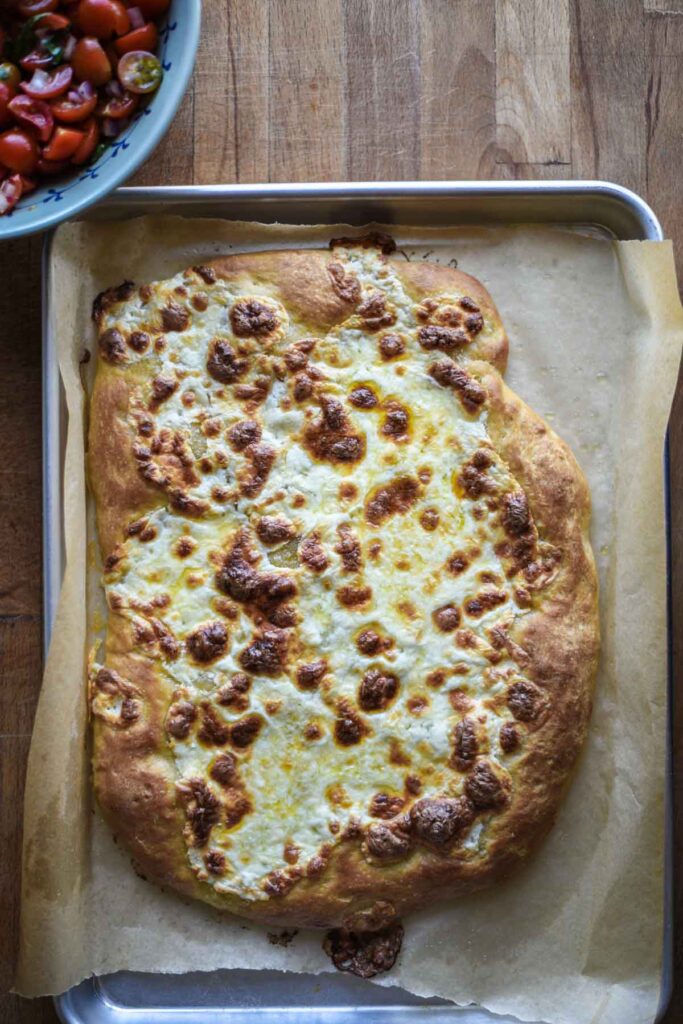 Cooked pizza dough with bubbly cheese.