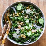 Kale and White Bean Salad in a bowl with serving utensils.